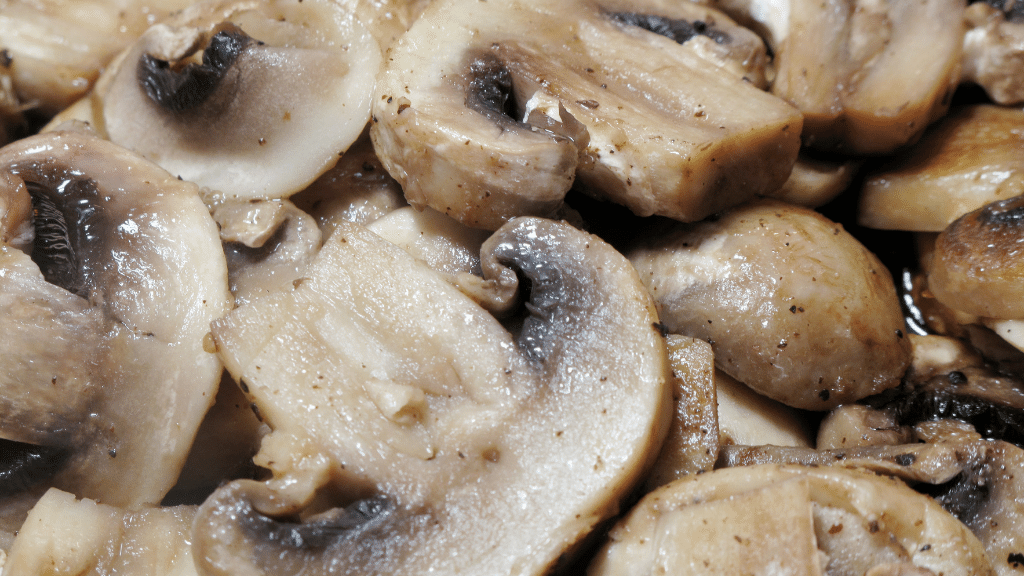 sliced mushrooms cooking in a pan
